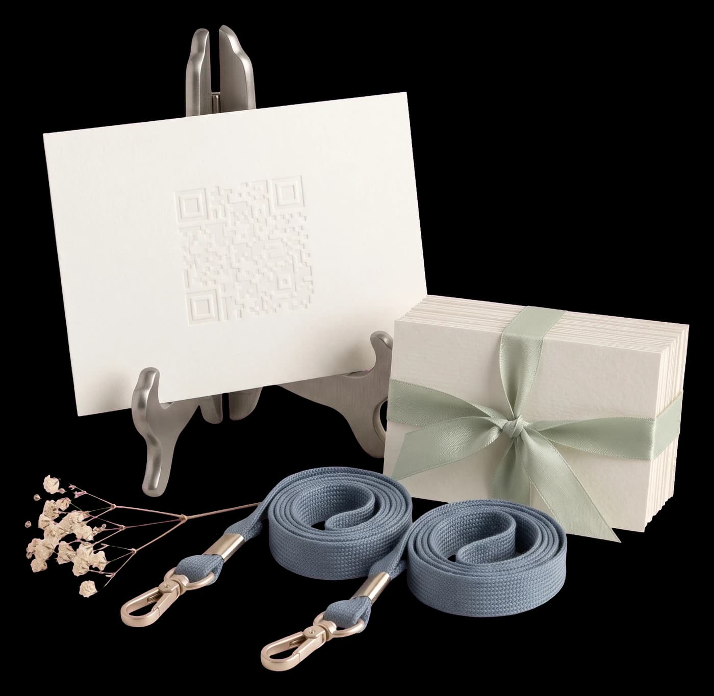 A corporate check-in arrangement: an embossed QR card on a pewter easel, a stack of name badges tied with ribbon, and two lanyards